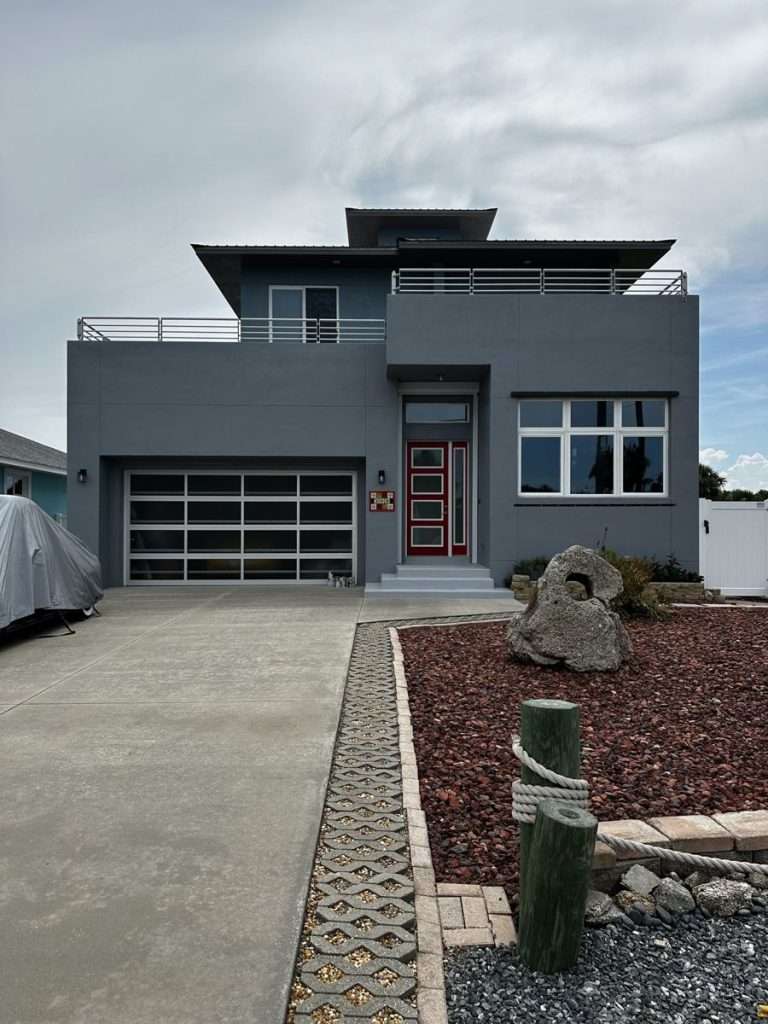 Finished gray exterior of a Flagler Beach home with white garage and railings