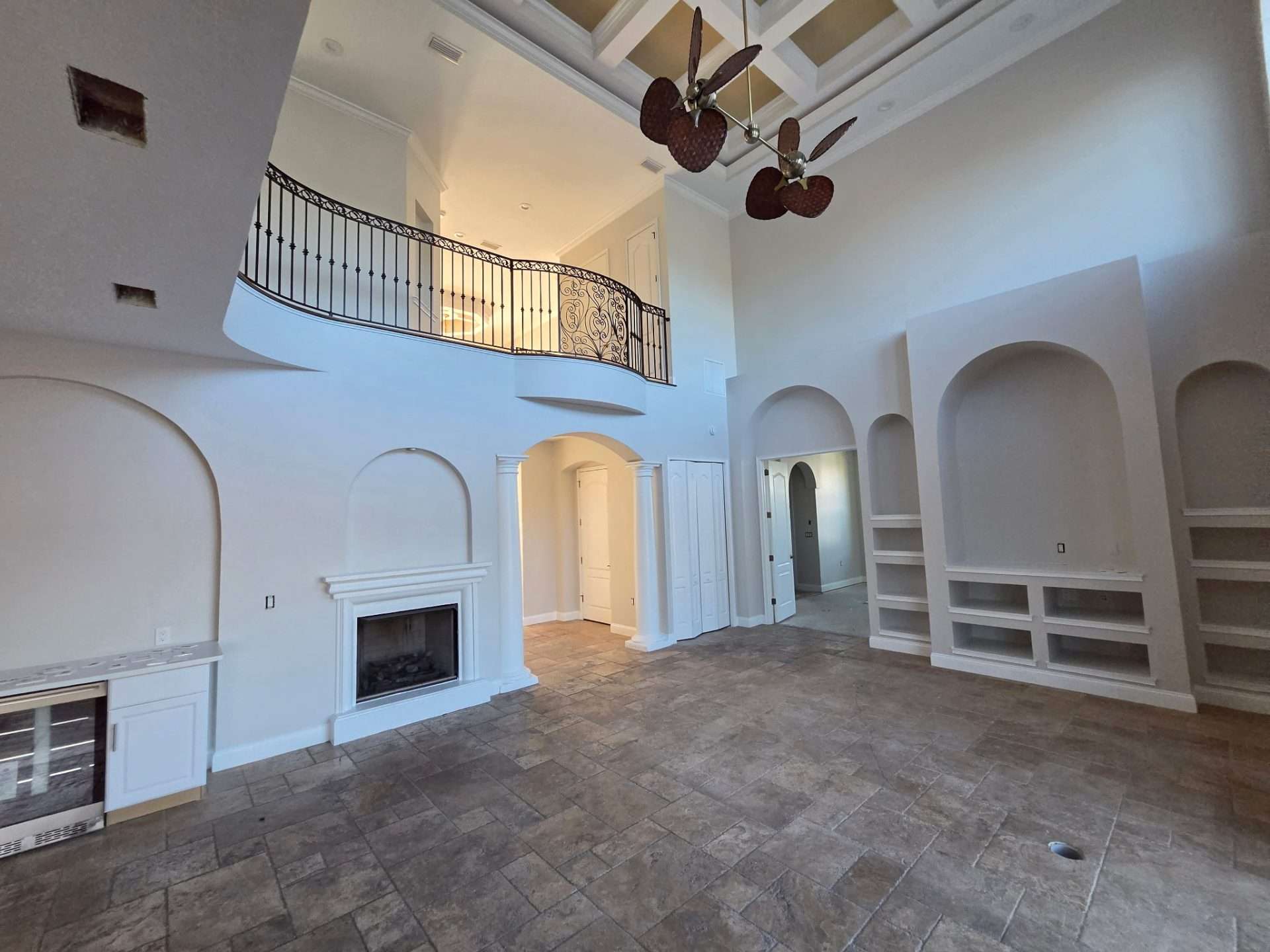 Two-story Palm Coast living room with neutral painted walls, white fireplace and built-in shelving